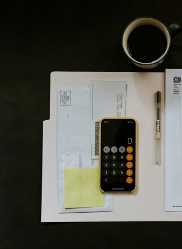 black Android smartphone near ballpoint pen, tax withholding certificate on top of white folder